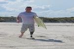 Man With Prosthetic Leg In Sand With Surfboard