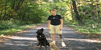 Amputee Standing On Prosthetic Leg With Dog Looking Up to Them